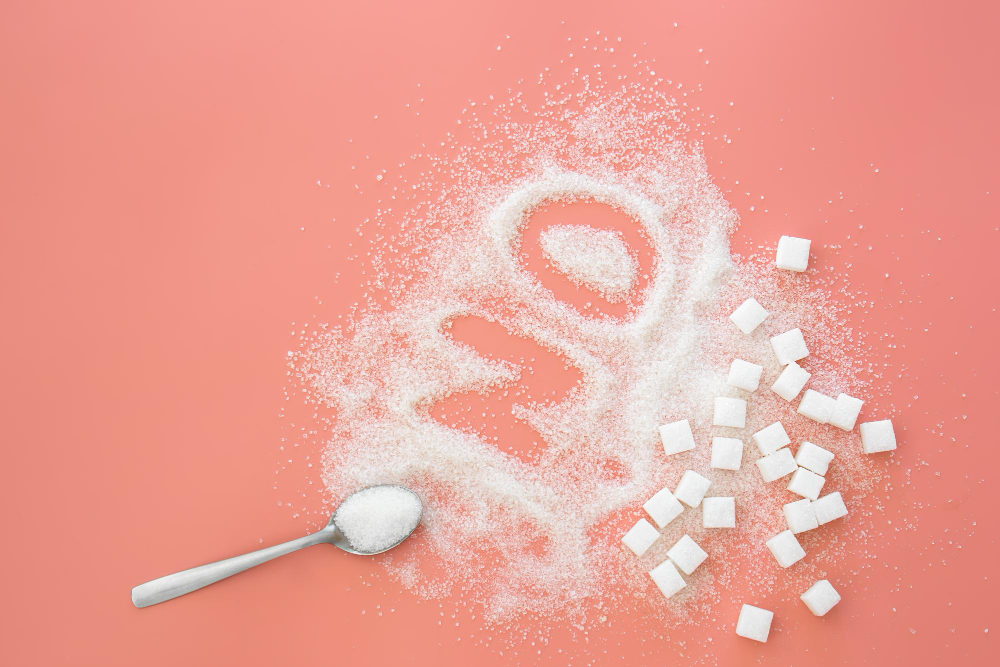 a spoon and sugar on a pink surface